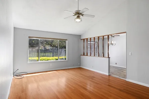 a view of an empty room with a window and wooden floor