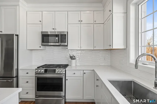 a kitchen with stainless steel appliances granite countertop a refrigerator a sink a stove a microwave a center island and cabinets