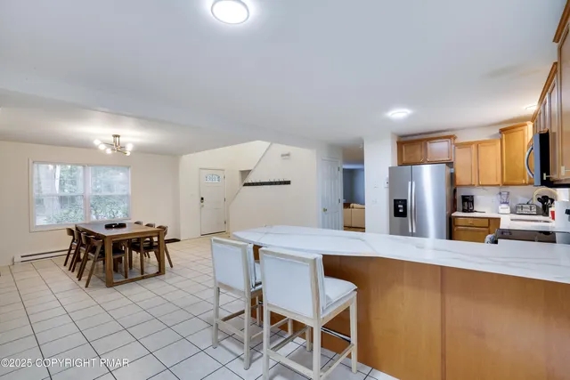 a kitchen with stainless steel appliances kitchen island granite countertop a table chairs and a refrigerator