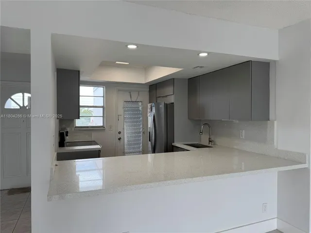 a kitchen with granite countertop a refrigerator and a sink