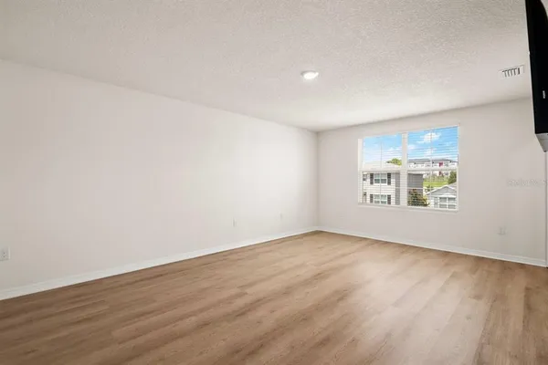 a view of an empty room with wooden floor and a window