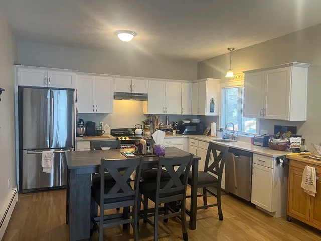 a kitchen with a dining table chairs refrigerator and cabinets
