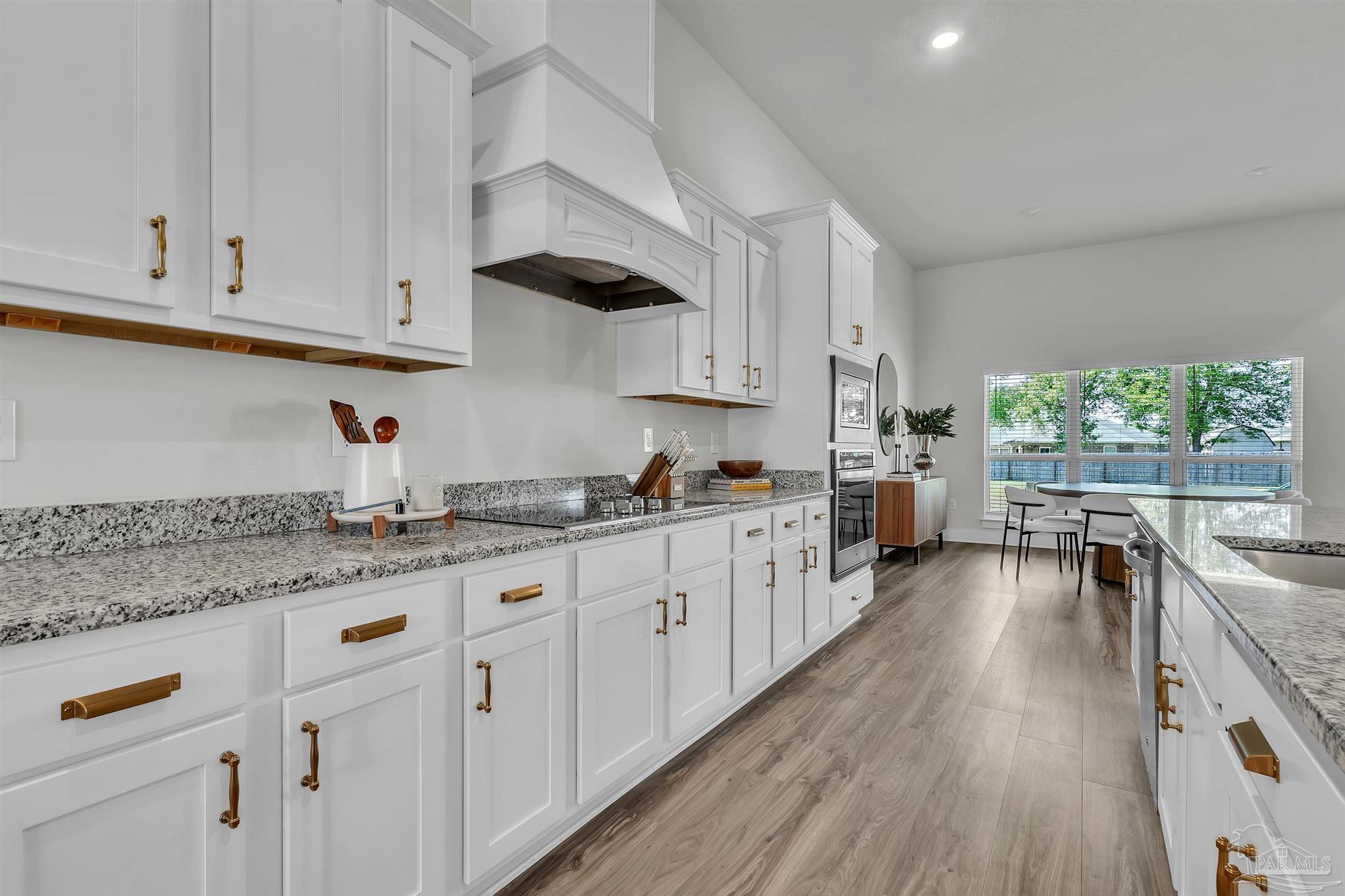 5531 Blake Lane Pace, FL 32571 - Photo 9 of 43 a kitchen with granite countertop lots of white cabinets and wooden floor