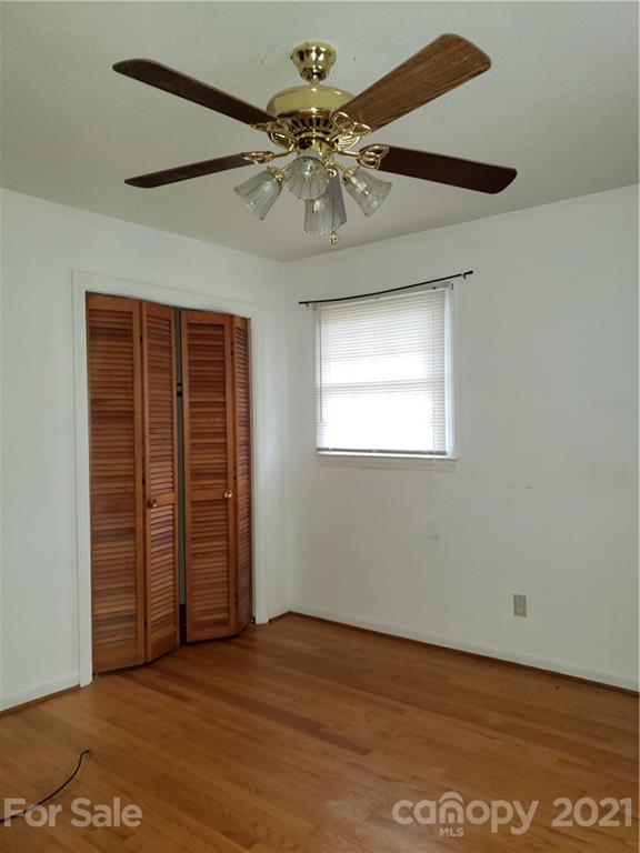 3718 Morgan Mill Road Monroe, NC 28110 - Photo 7 of 13 an empty room with wooden floor chandelier fan and windows