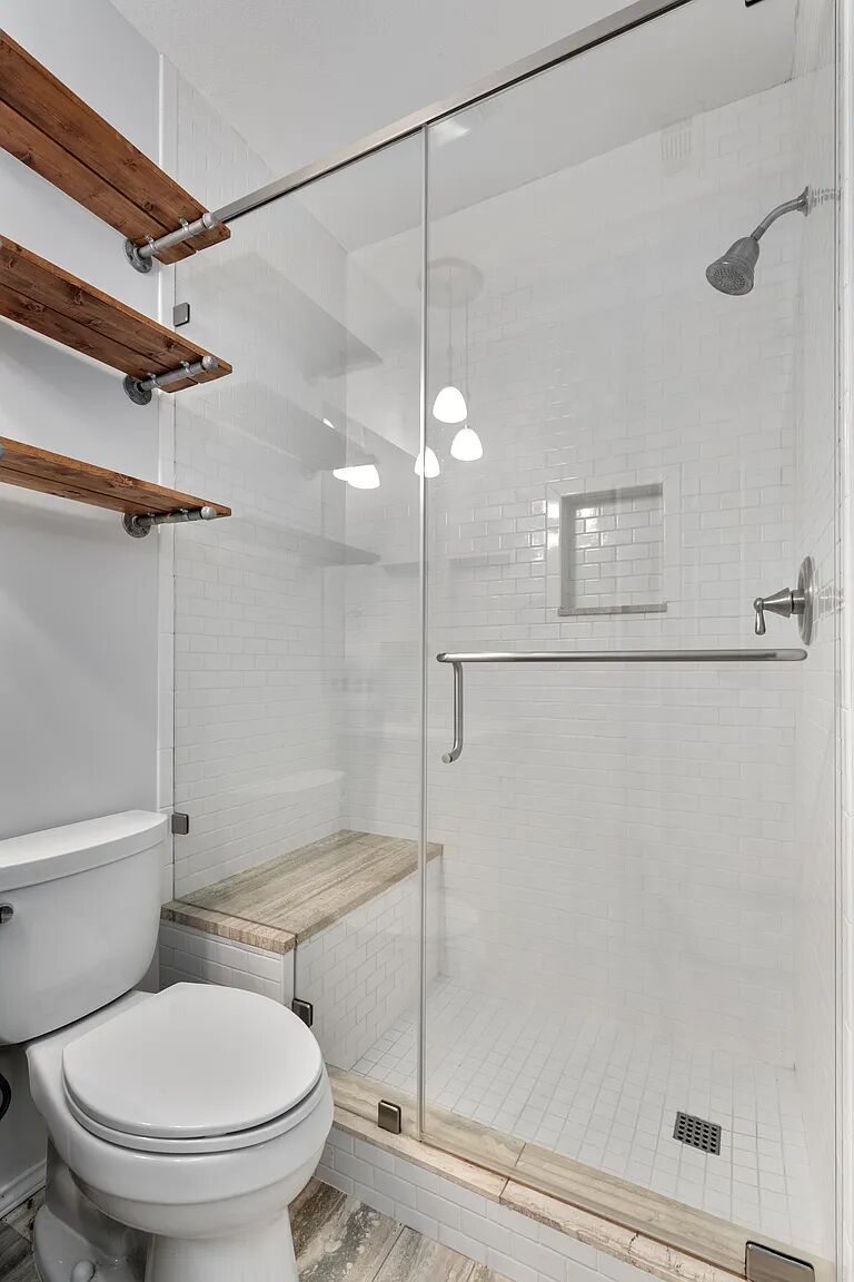 11970 Jollyville Road, Unit 202 Austin, TX 78759 - Photo 15 of 25 A well-lit, tiled shower with a built-in bench and glass enclosure offers a refreshing start to your day.