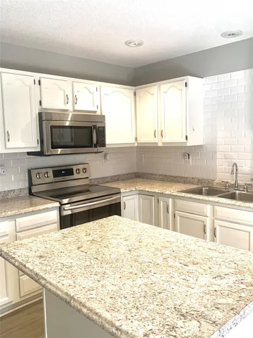 a kitchen with stainless steel appliances kitchen island granite countertop a sink dishwasher stove and microwave with wooden floor