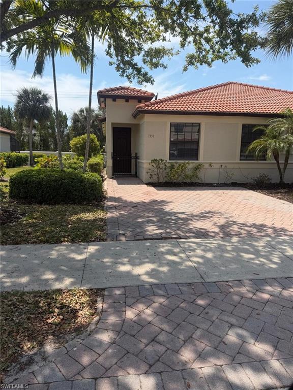 7350 Bristol Circle Naples, FL 34120 - Photo 2 of 8 a front view of a house with a garden and trees