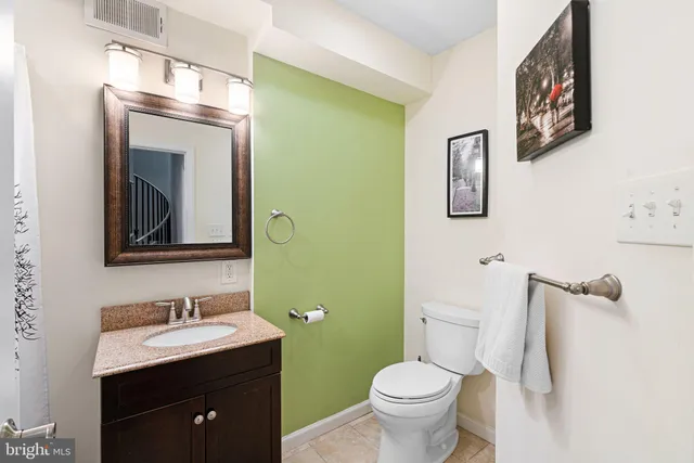 a bathroom with a granite countertop toilet sink and mirror
