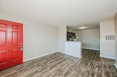 308 South Hoskins Road, Unit D Charlotte, NC 28208 - Photo 7 of 19 an empty room with wooden floor and a kitchen