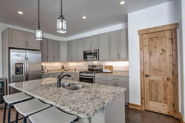 a kitchen with kitchen island granite countertop stainless steel appliances a sink stove refrigerator and cabinets