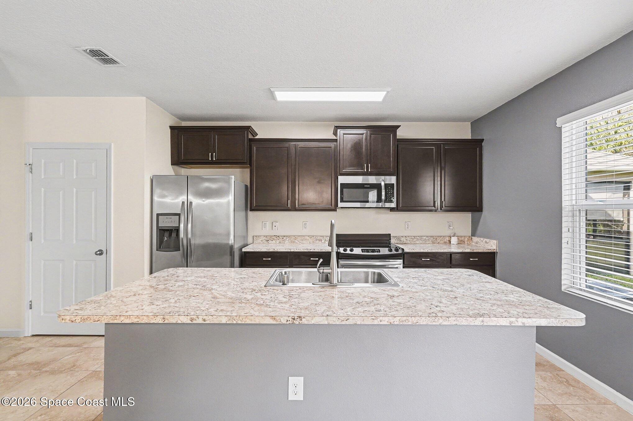 2535 Falcon Lane Mims, FL 32754 - Photo 12 of 31 a kitchen with stainless steel appliances granite countertop a sink and a refrigerator