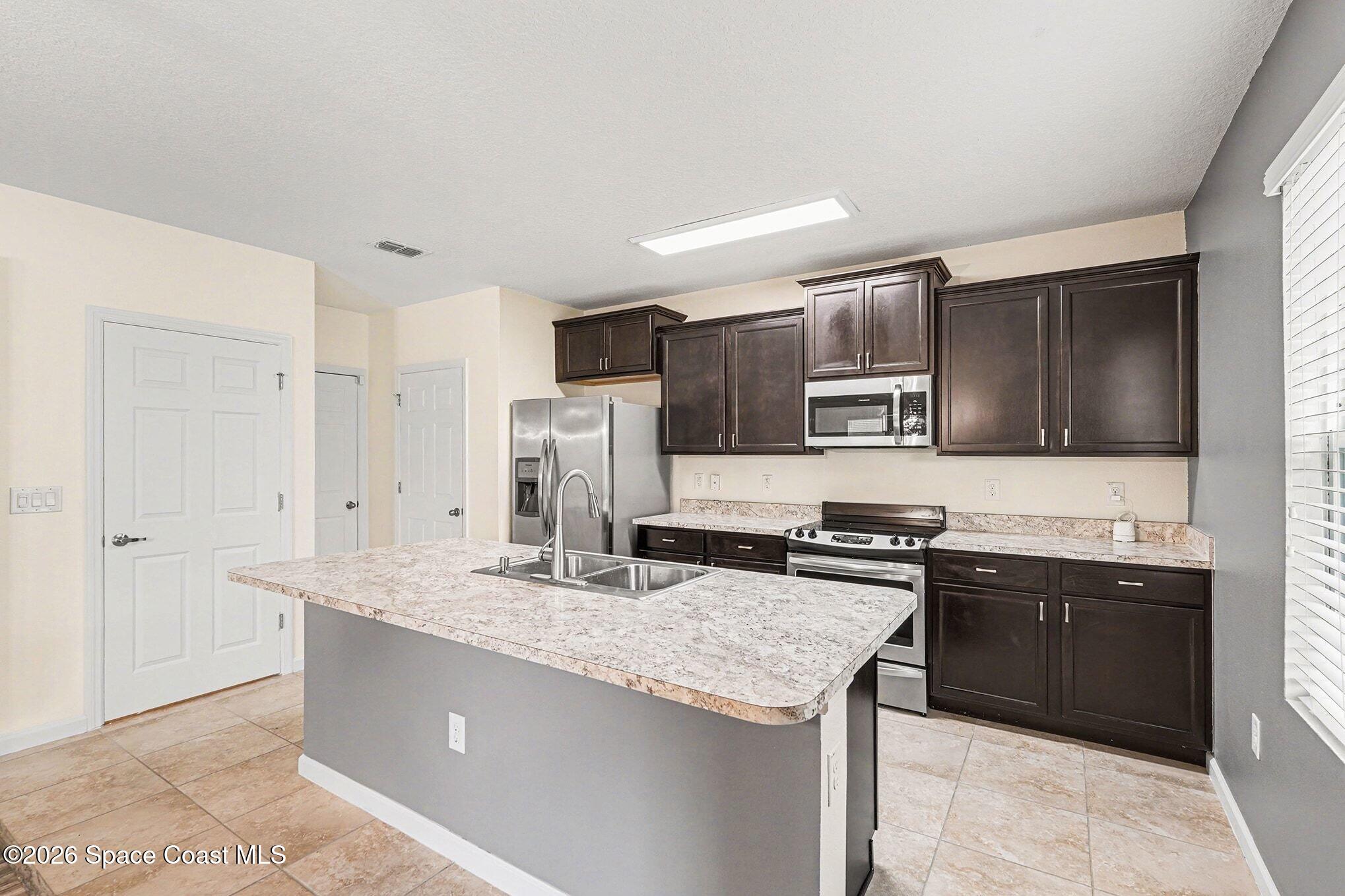 2535 Falcon Lane Mims, FL 32754 - Photo 13 of 31 a kitchen with stainless steel appliances granite countertop a sink stove microwave and refrigerator