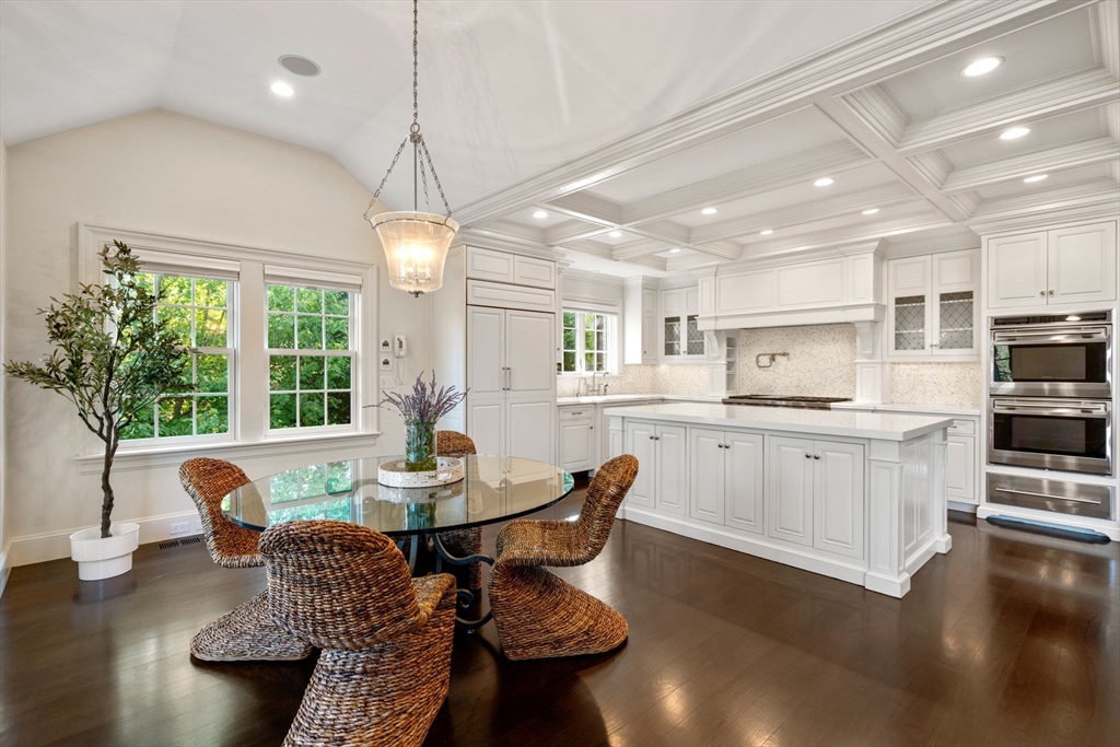 27 Pine Summit Circle, Unit 27 Weston, MA 02493 - Photo 3 of 42 a kitchen with kitchen island granite countertop a stove a sink a dining table and chairs with wooden floor