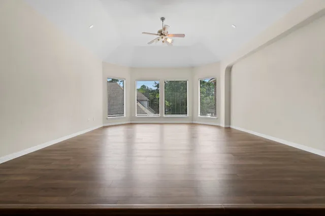 a view of empty room with wooden floor and fan