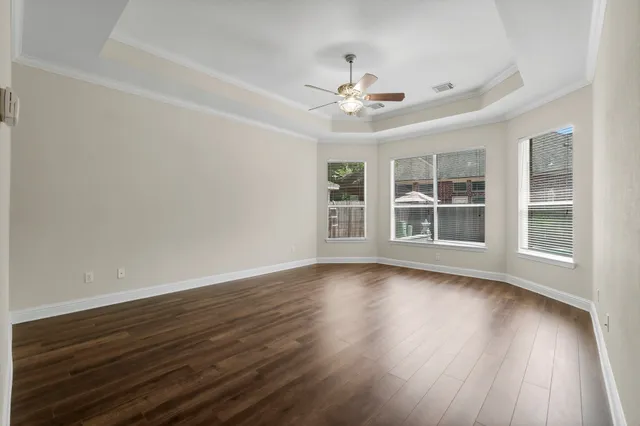 an empty room with wooden floor and windows