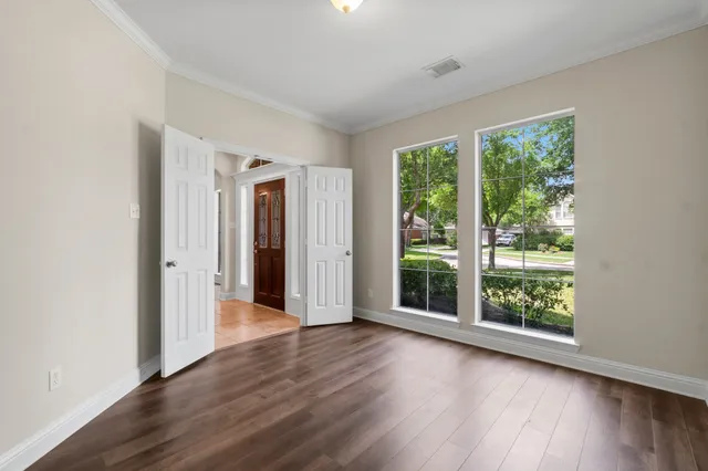 a view of an empty room with wooden floor and a window