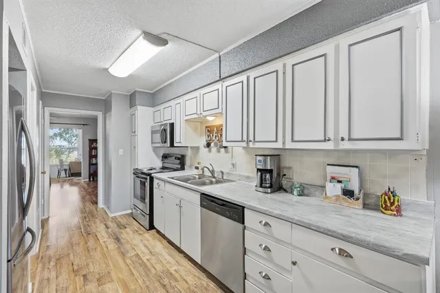 a kitchen with stainless steel appliances granite countertop a sink dishwasher stove and white cabinets with wooden floor