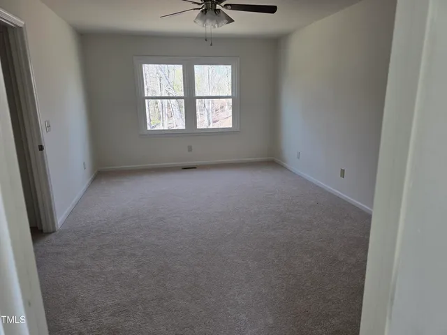 an empty room with a window and a ceiling fan