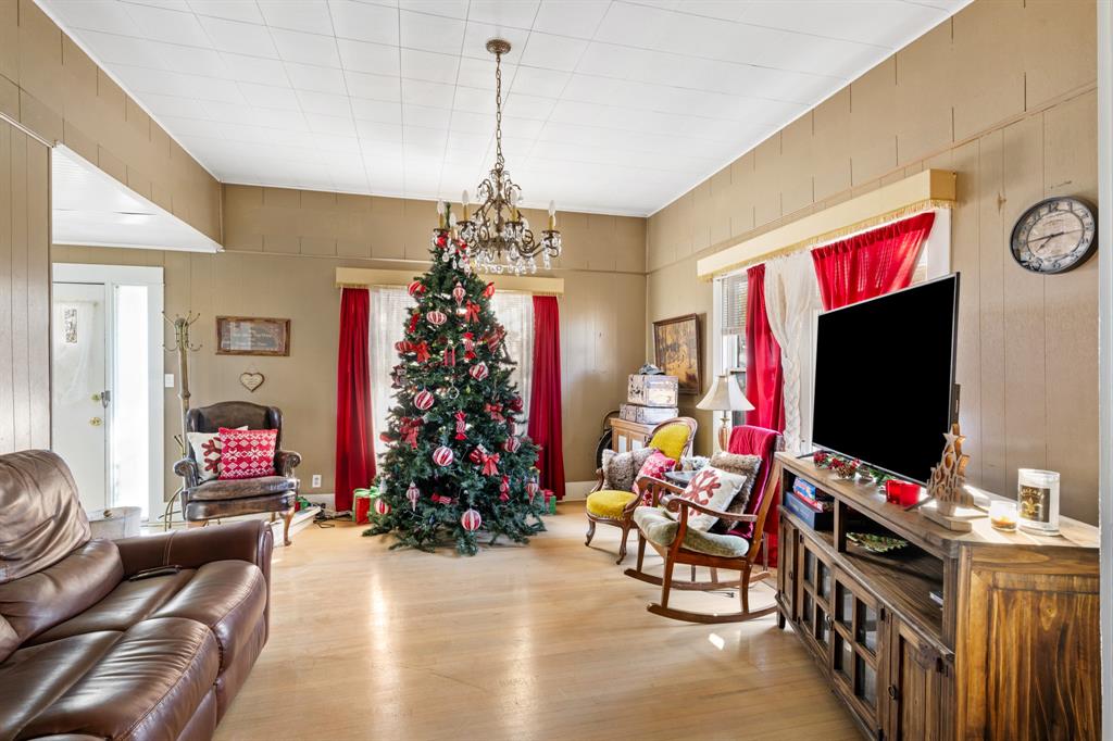 308 Race Street Baird, TX 79504 - Photo 14 of 27 Living room featuring wood finished floors, a chandelier, and wooden walls