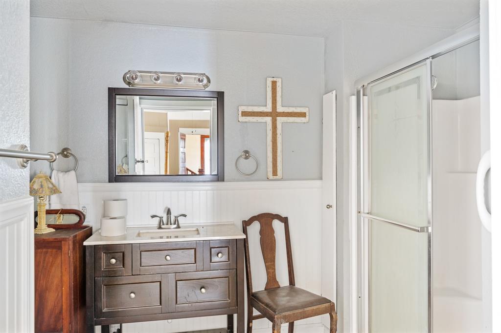 308 Race Street Baird, TX 79504 - Photo 18 of 27 Full bathroom featuring wainscoting, vanity, a shower stall, and a decorative wall