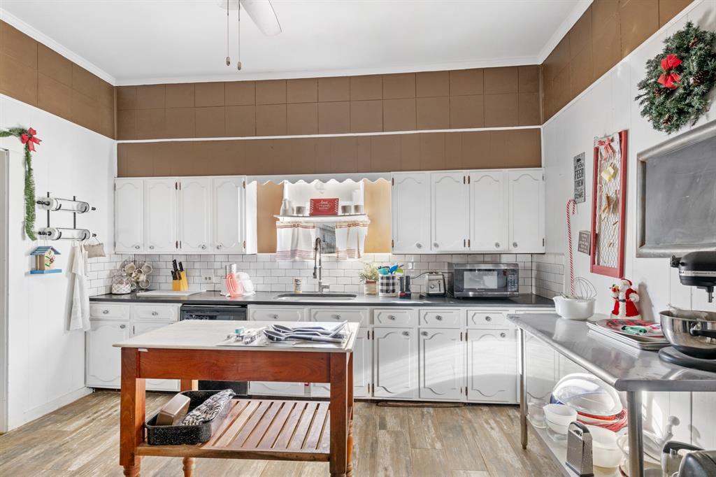 308 Race Street Baird, TX 79504 - Photo 2 of 27 Kitchen featuring dark countertops, white cabinets, light wood-style floors, decorative backsplash, and crown molding