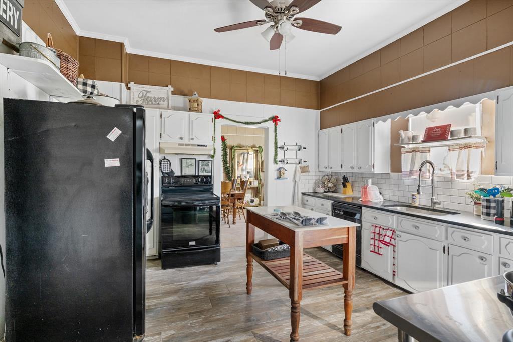 308 Race Street Baird, TX 79504 - Photo 8 of 27 Kitchen featuring black appliances, white cabinetry, crown molding, light wood-style flooring, and dark countertops