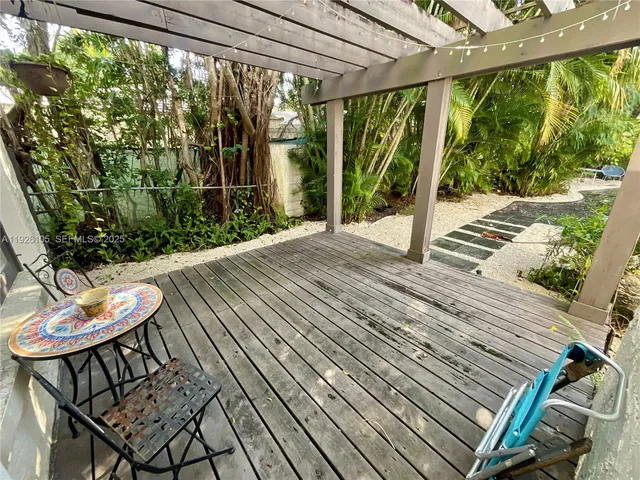 a view of a patio with table and chairs potted plants with wooden floor and floor to ceiling window