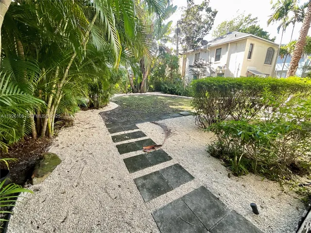 a view of a yard with plants and large trees