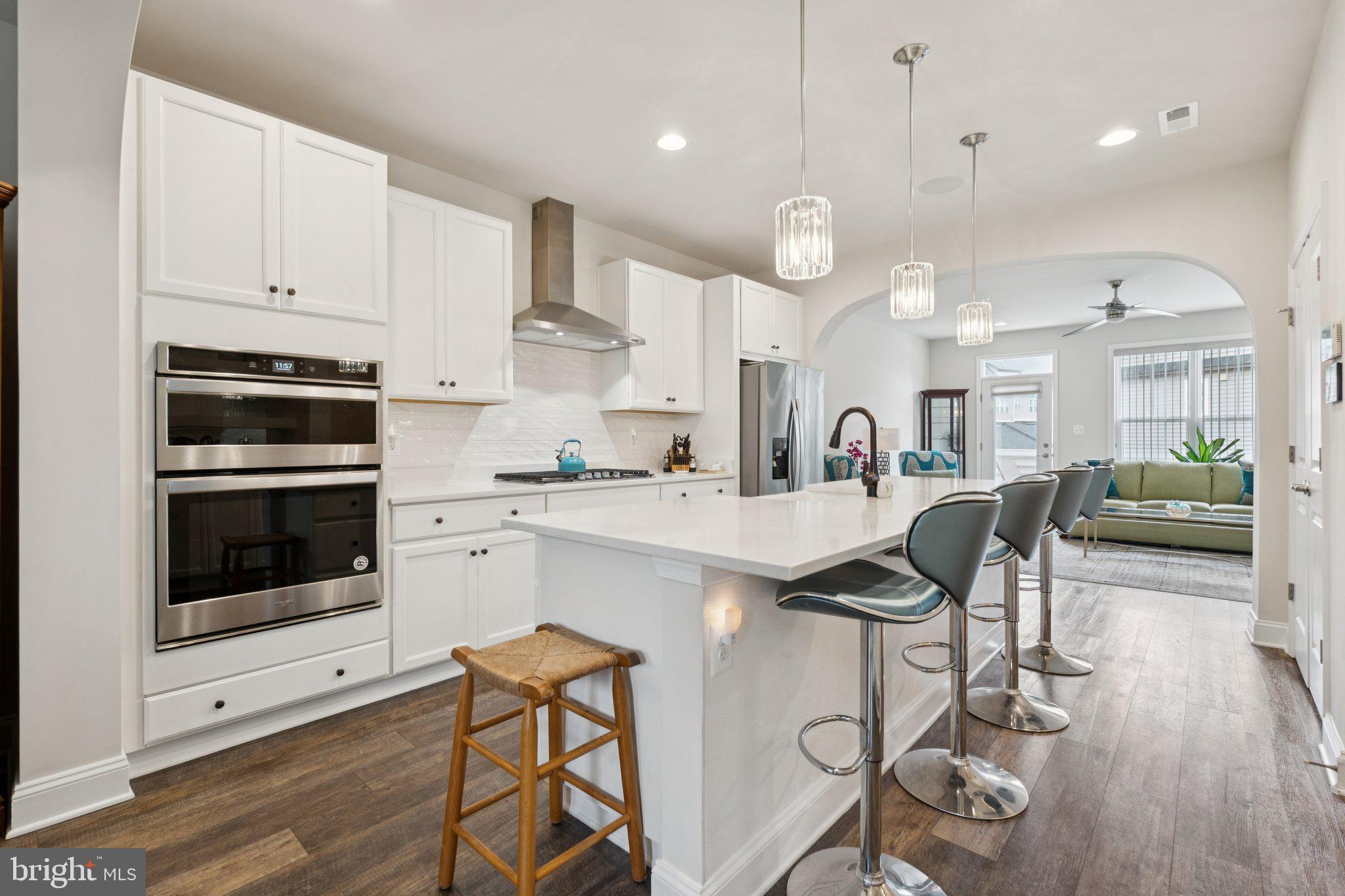 969 Holden Road Frederick, MD 21701 - Photo 7 of 35 a kitchen with stainless steel appliances kitchen island granite countertop a stove a sink a refrigerator and white cabinets with wooden floor