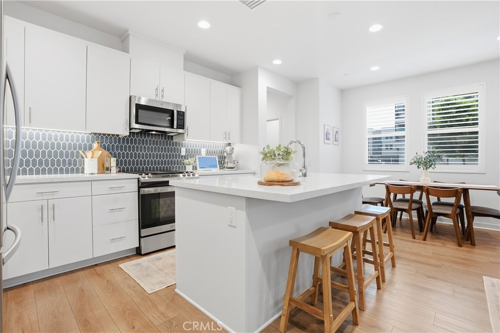 451 Potter Way Rancho Mission Viejo, CA 92694 - Photo 3 of 75 a kitchen with stainless steel appliances a white table chairs and a refrigerator