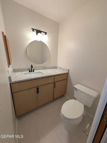a bathroom with a granite countertop toilet sink mirror and vanity