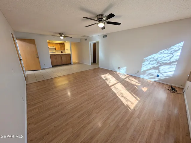 a view of empty room with wooden floor and fan