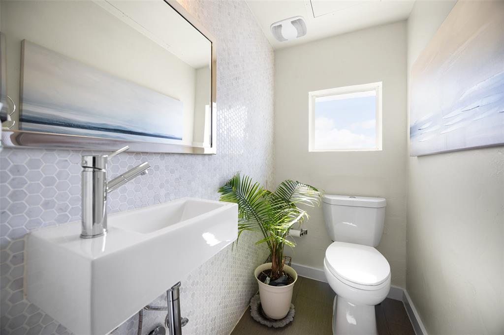 3922 Gilbert Avenue, Unit 214 Dallas, TX 75219 - Photo 19 of 27 Contemporary bathroom featuring a sleek rectangular vessel sink, polished chrome faucet, hexagonal tile backsplash, and a modern toilet