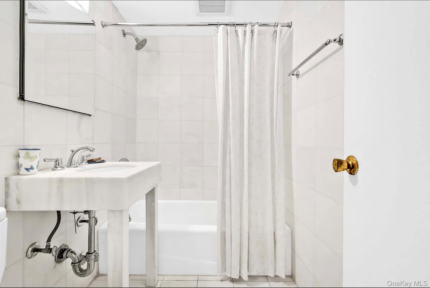 30-44 29th Street, Unit 6D Queens, NY 11102 - Photo 10 of 15 a bathroom with a sink a mirror and a shower