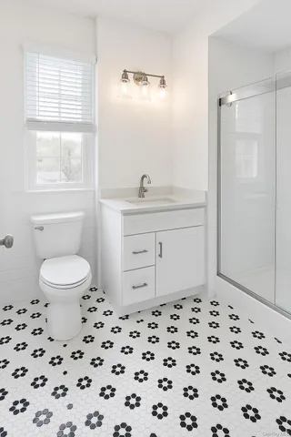 a bathroom with a sink a toilet a window and shower