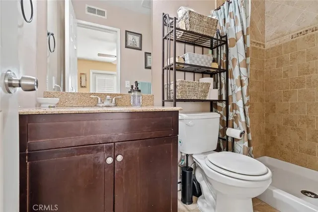 a bathroom with a granite countertop toilet sink and mirror
