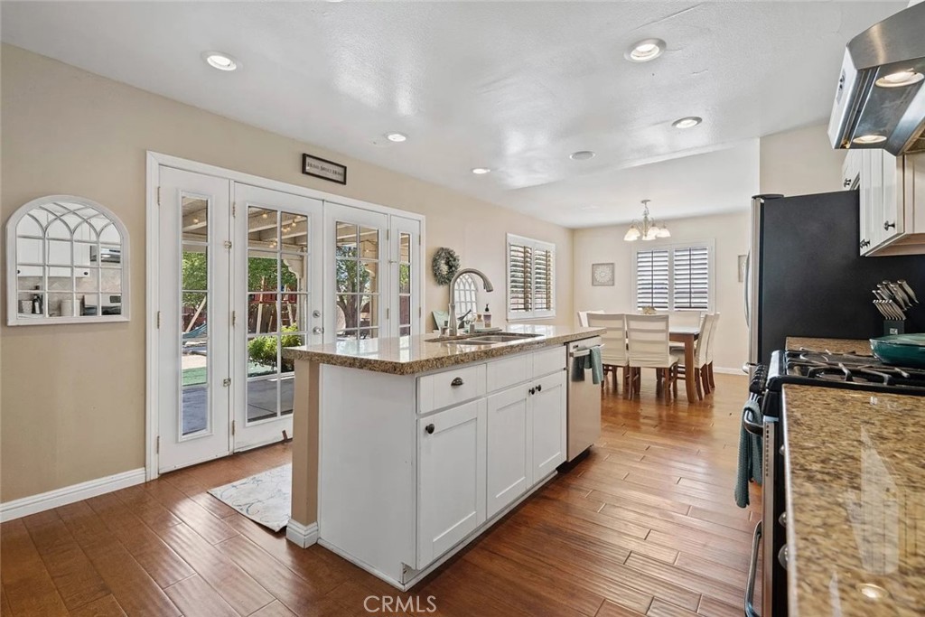 14022 Arlee Place Sylmar, CA 91342 - Photo 9 of 33 a kitchen with stainless steel appliances granite countertop a refrigerator a stove a sink dishwasher and a dining table with wooden floor