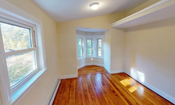 a view of an empty room with wooden floor and a window