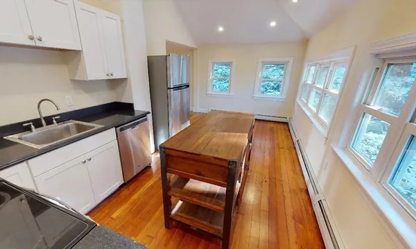 a kitchen that has a sink wooden floor and stainless steel appliances