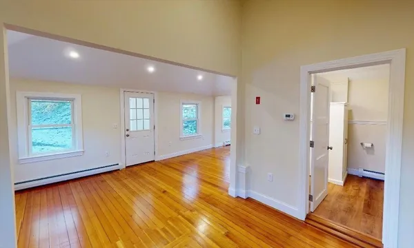 a view of an empty room with wooden floor and a window