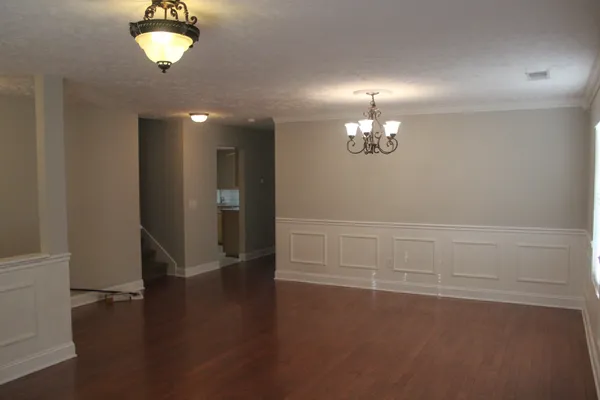 an empty room with wooden floor chandelier and windows