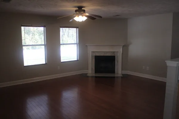 an empty room with wooden floor fireplace and windows