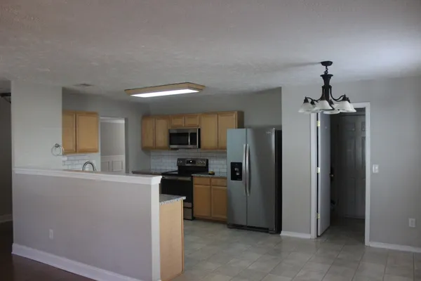 a kitchen with stainless steel appliances granite countertop a refrigerator a sink dishwasher a stove and a dining table with wooden floor