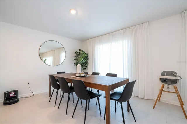 a kitchen with stainless steel appliances granite countertop a refrigerator a sink a stove a dining table and chairs with white cabinets