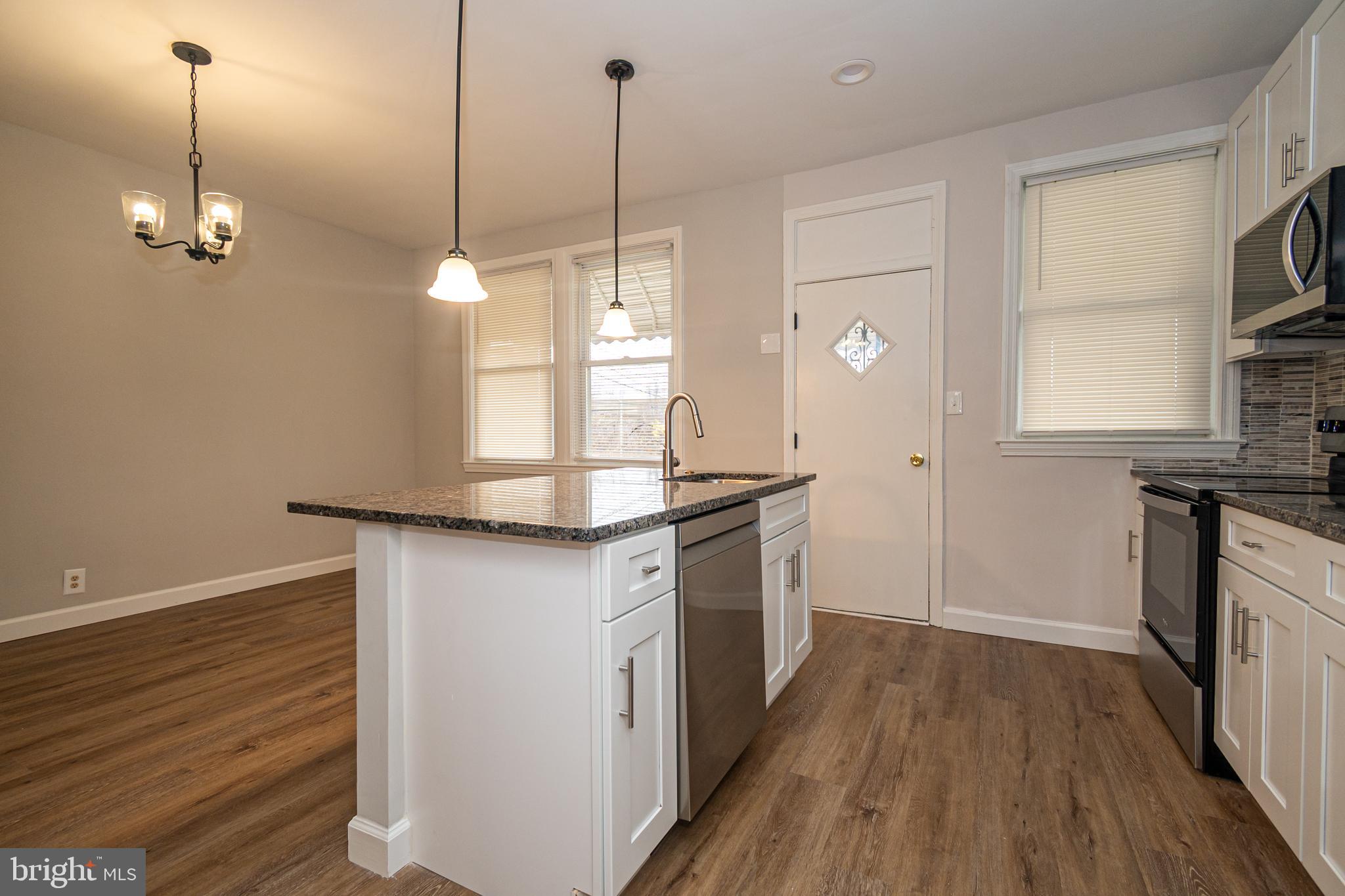 3716 Columbus Drive Baltimore, MD 21215 - Photo 11 of 36 a kitchen with kitchen island granite countertop a stove a sink a center island a refrigerator and a wooden floor