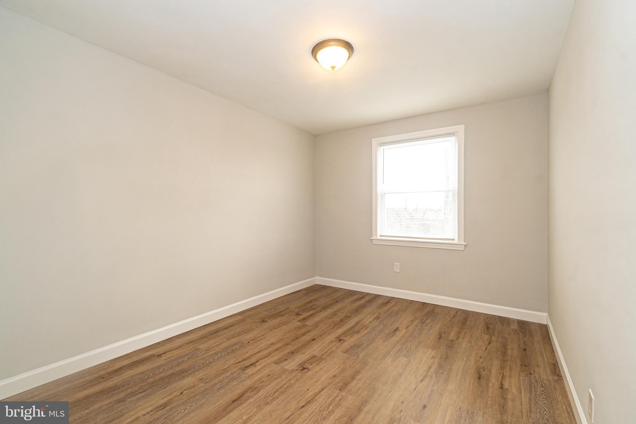 3716 Columbus Drive Baltimore, MD 21215 - Photo 19 of 36 an empty room with wooden floor and windows