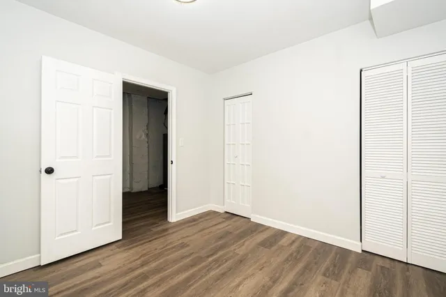 a view of an empty room with wooden floor and closet