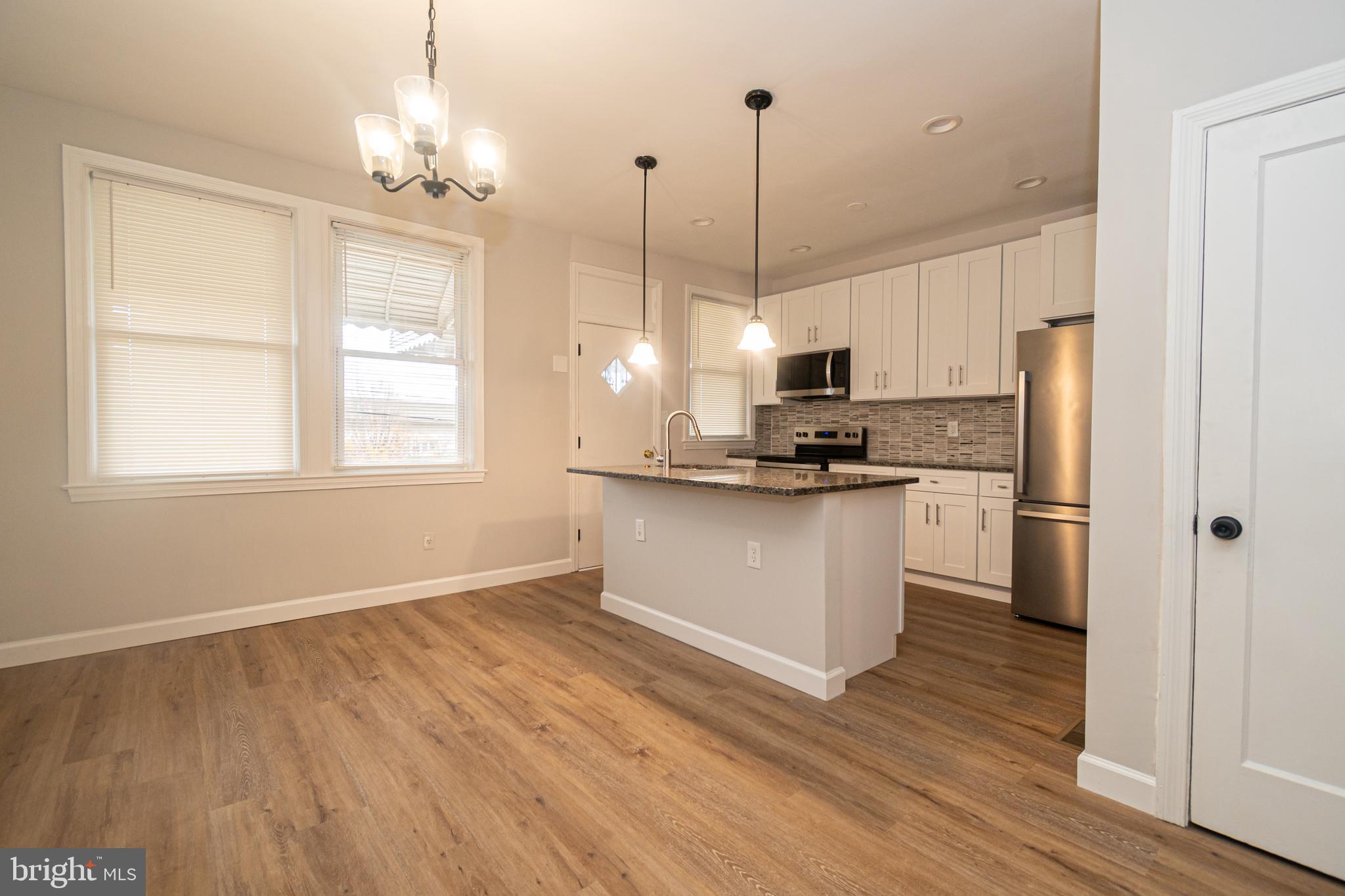 3716 Columbus Drive Baltimore, MD 21215 - Photo 8 of 36 a kitchen with stainless steel appliances granite countertop a refrigerator a sink dishwasher a stove and white cabinets with wooden floor