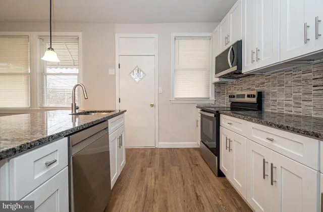a kitchen with kitchen island granite countertop a sink cabinets stainless steel appliances and a counter space