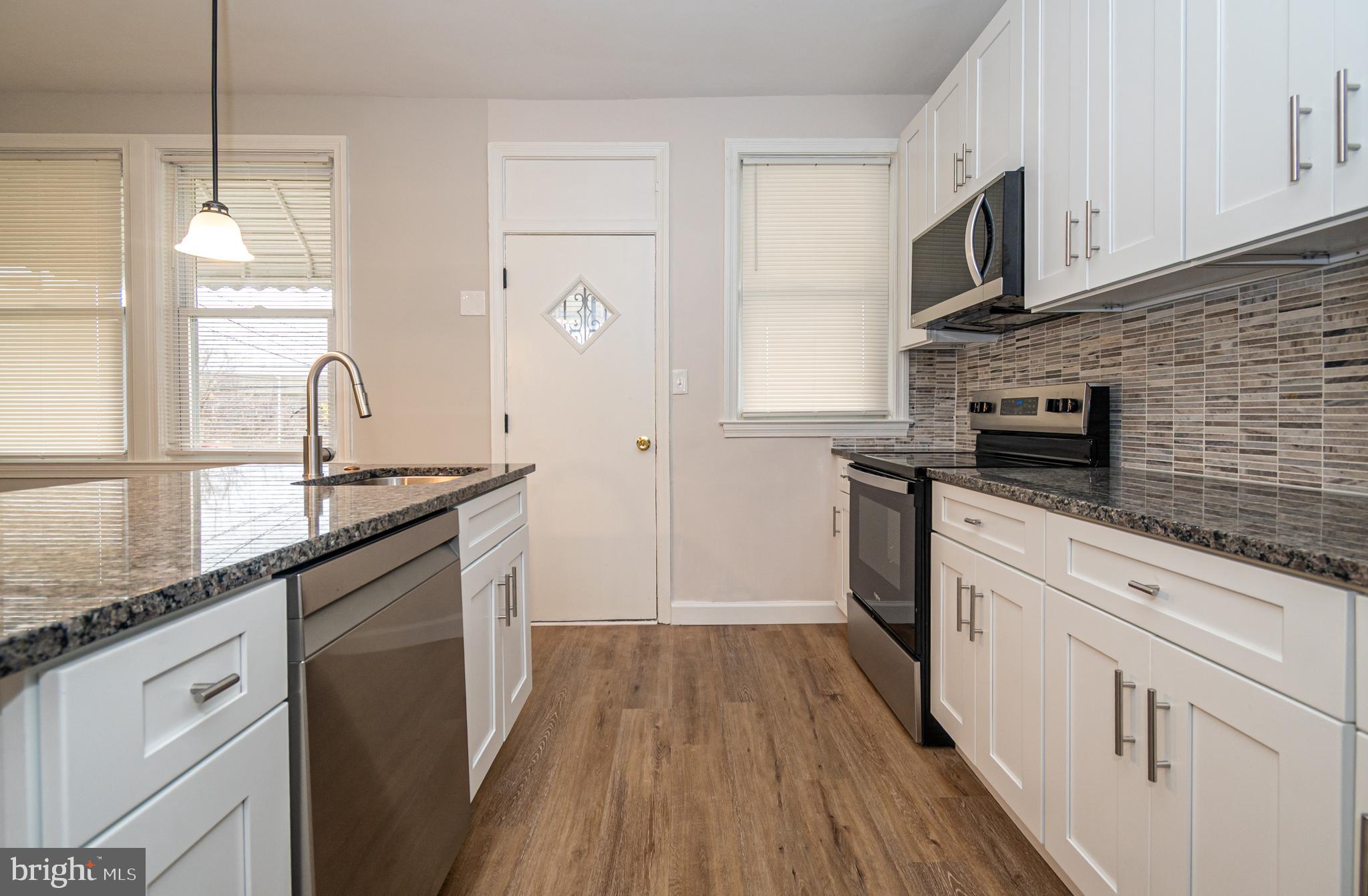 3716 Columbus Drive Baltimore, MD 21215 - Photo 9 of 36 a kitchen with kitchen island granite countertop a sink cabinets stainless steel appliances and a counter space